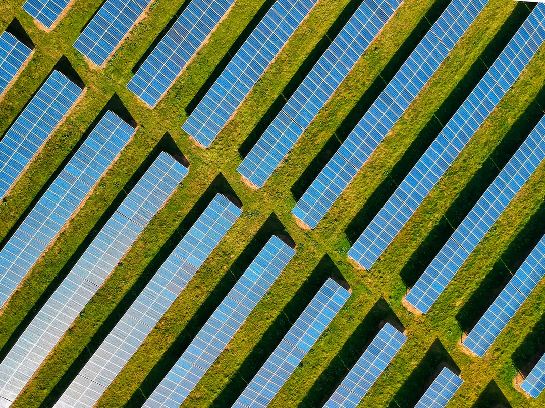 空拍視角下整齊排列在綠地上的太陽能板陣列，象徵發電效率是太空運算的主要誘因