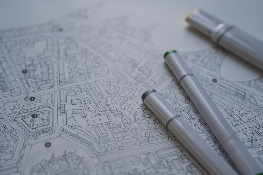 桌面上一張細密線稿城市地圖與三支繪圖筆，象徵先把網站的頁面類型分清楚，再決定每一類要標記什麼