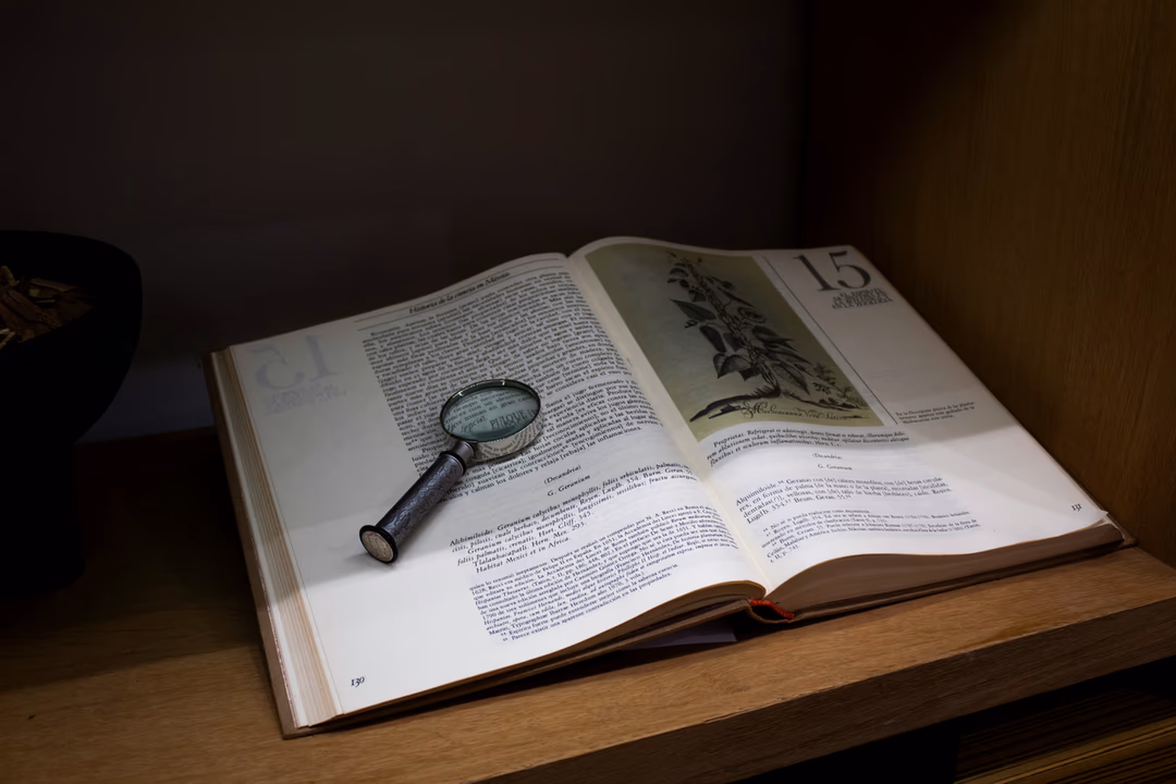 昏暗書桌上一本攤開的厚書，上面擺著一只舊式放大鏡，象徵發布前逐項核對、出事後回頭查紀錄