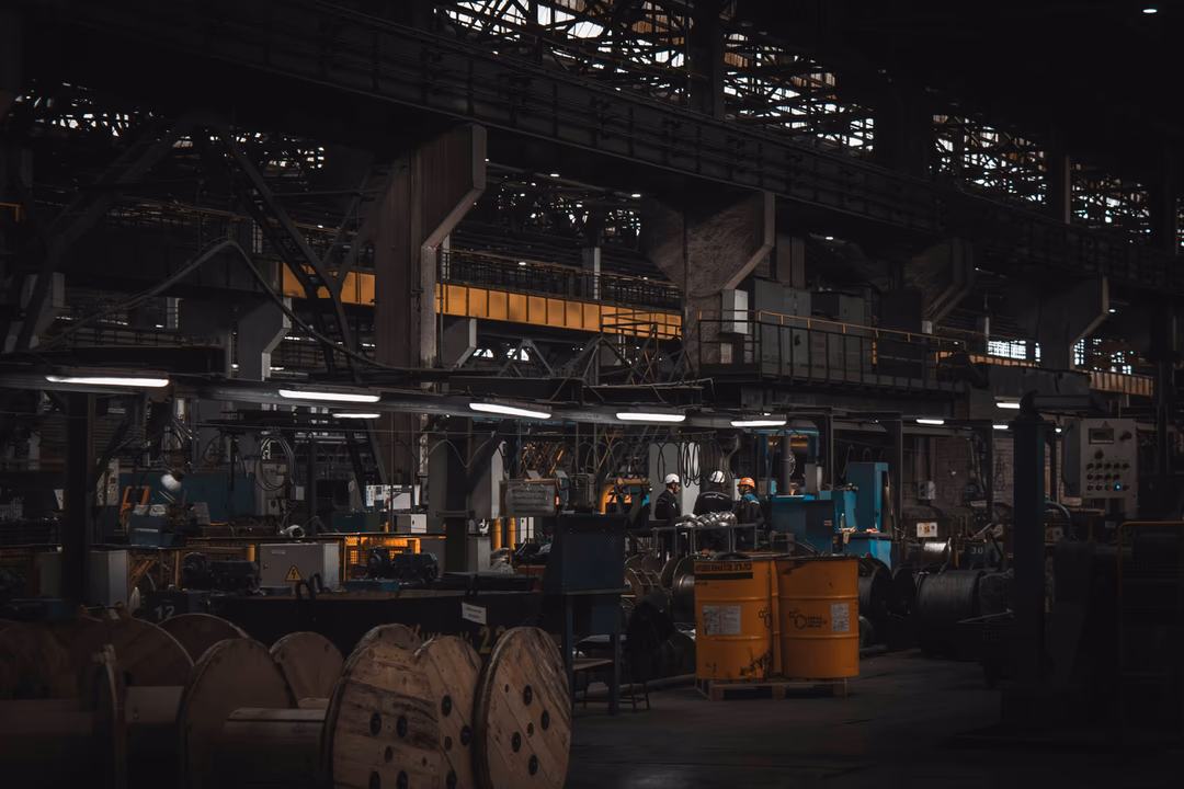 昏暗的大型廠房內部，機具、天車與作業區分布在不同樓層，象徵一家工廠裡同時存在數十個分屬不同法規、不同週期的受檢項目