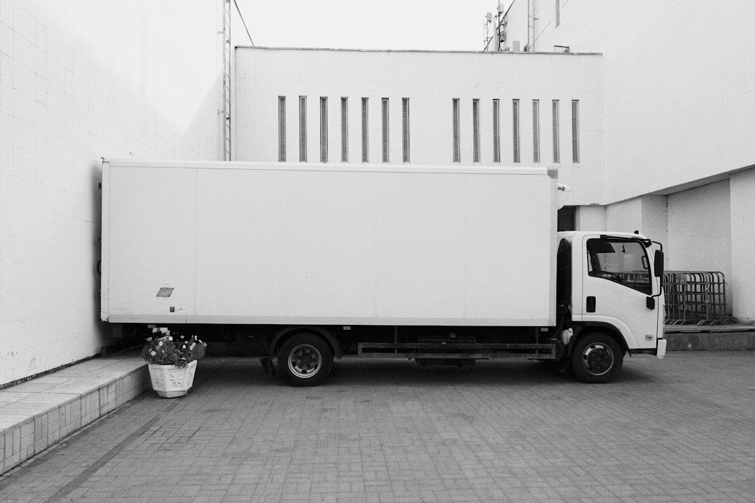 一輛白色廂型貨車停在建築物旁沒有移動，象徵訂單在超出授信額度時被擋下、暫緩出貨的那一刻